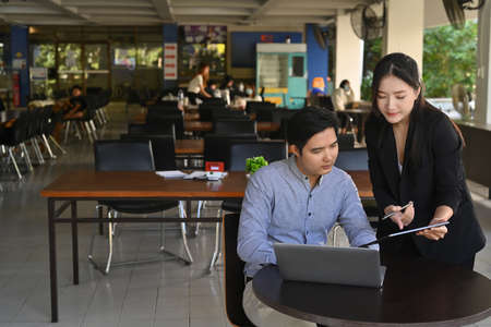 Two young business colleagues working on new project together in bright office.