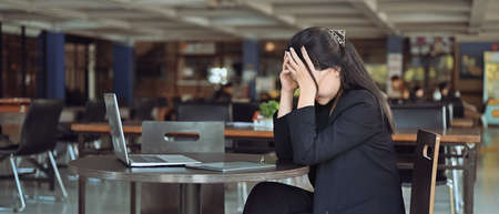 Frustrated business woman felling stress while sitting at her office desk.の写真素材