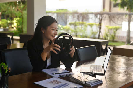Attractive businesswoman holding headphone and watching webinar on laptop computer.の写真素材