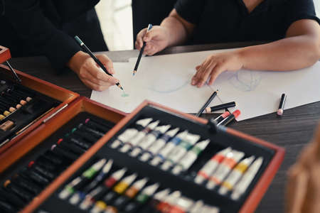 Cropped shot teacher helping children drawing pictures in art class.の写真素材