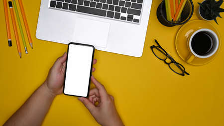 Overhead view man using smart phone at creative workspace.の写真素材