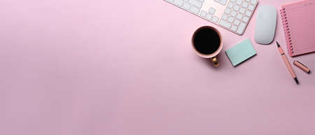 Female workspace with coffee cup, sticky note and notebook on pink background.の写真素材