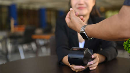 Cropped image of customer paying through smart watch at coffee shop.の写真素材