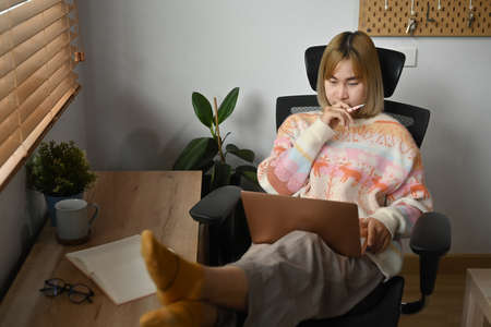 Casual young woman browsing internet with laptop at home.の写真素材