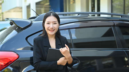 Attractive businesswoman is standing near her car and smiling to camera.の写真素材