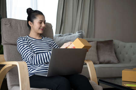 Happy woman opening parcel package at home.の写真素材
