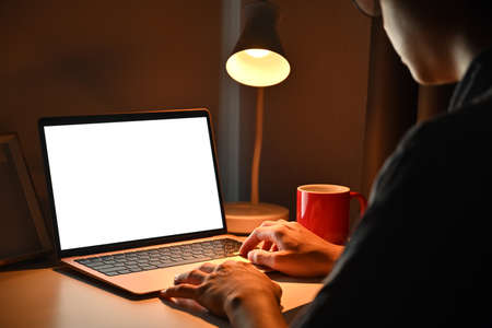 Young man laying on bed and working with computer tablet at late night.の写真素材
