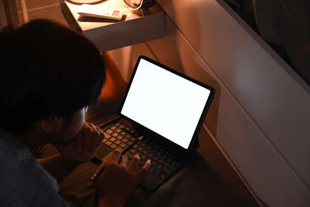 Man browsing internet with computer table at night in bedroom.の写真素材