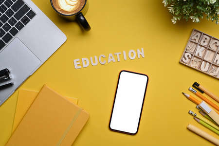 Top view smart phone, laptop computer and stationery on yellow background. Back to school concept.の写真素材
