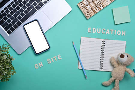 Above view smart phone, laptop computer and notebook on blue background.