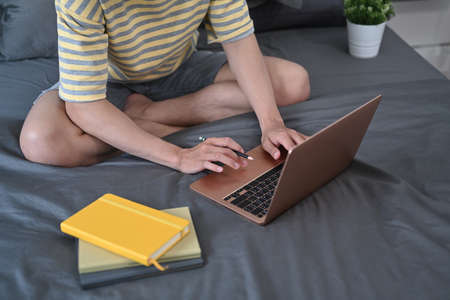 Man working online with computer laptop on comfortable bed.の写真素材