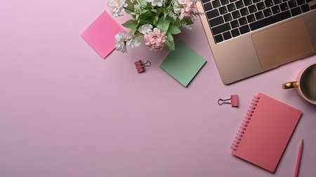 Feminine workplace with laptop computer, sticky notes and coffee cup on pink background.の写真素材