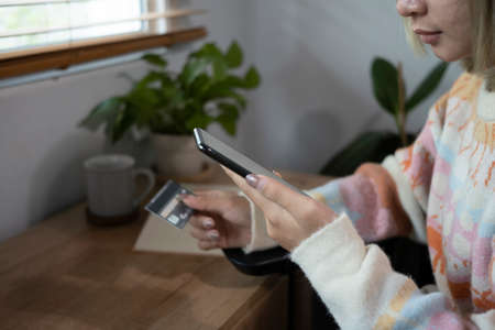 Cropped shot woman holding credit card and having backing online on smart phone.