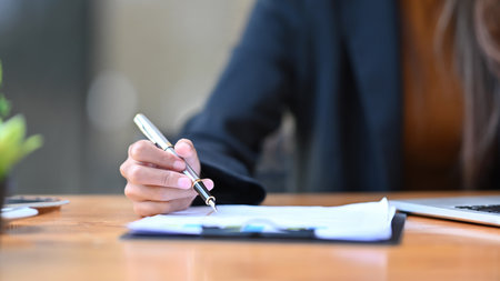 Cropped shot businesswoman holding pen and signing on document.の写真素材