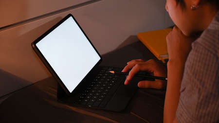 Cropped shot young man lying on comfortable bed and working with computer tablet at late night.