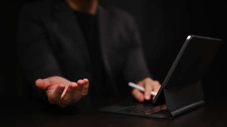 Cropped image of businessman using computer tablet and hand showing or holding something.の写真素材