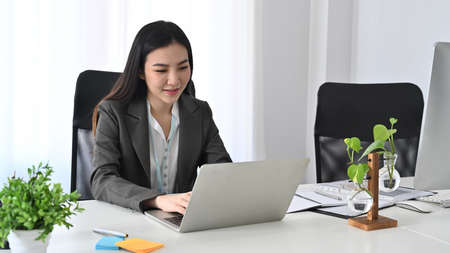 Confident businesswoman working with laptop computer in office.