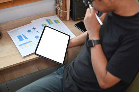 Serious man analyzing financial data on digital tablet at home.の写真素材