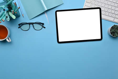 Mock up digital tablet, glasses, coffee cup and notebook on blue background.の写真素材