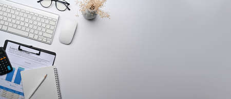 Top view cup of coffee, sticky note, wireless keyboard and potted plant on white table.の写真素材
