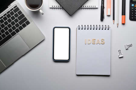 Top view smart phone, financial reports and notepad on white office desk.の写真素材