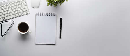 Top view empty notepad, coffee cup and potted plant on white table. Copy space.