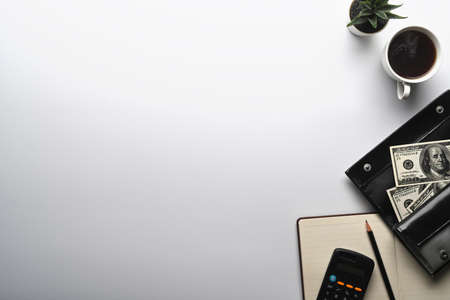 Top view calculator, dollar banknotes and notebook on white table. Economy and finance concept.の写真素材