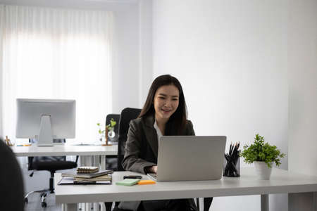 Side view beautiful businesswoman working with computer in modern workplace.の写真素材