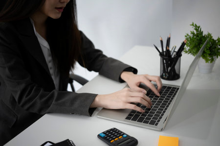Attractive businesswoman standing and checking reports at her office desk.