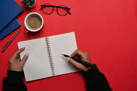 Overhead view young woman in warm sweater holding pen and wiring on notebook.の写真素材