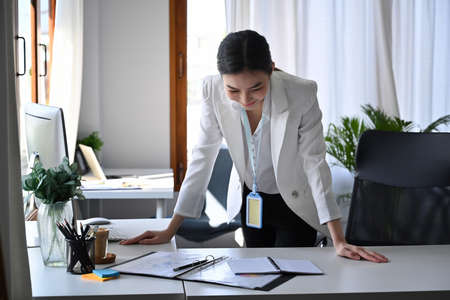 Rear view of businesswoman working on computer and checking financial document in  bright modern office.の写真素材