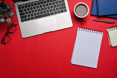Computer laptop, empty notebook, coffee cup and glasses on red background.の写真素材