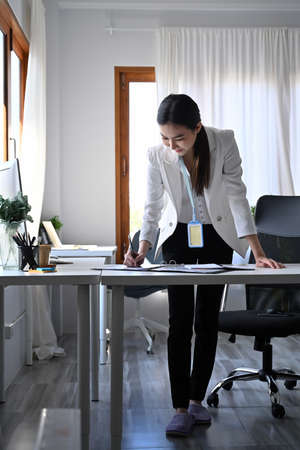 Smiling beautiful businesswoman holding credit card and shopping online with smart phone.の写真素材