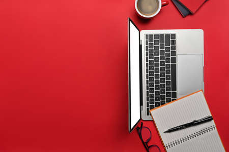 Mock up computer laptop, notebook and coffee cup on red background with copy space for text.の写真素材