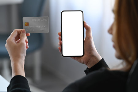 Over shoulder view businesswoman holding credit card and using smart phone.の写真素材