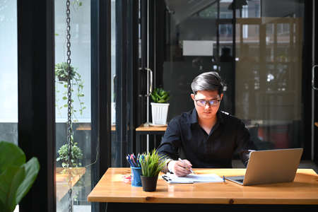 Young focused businessman analyzing statistical data at office desk.