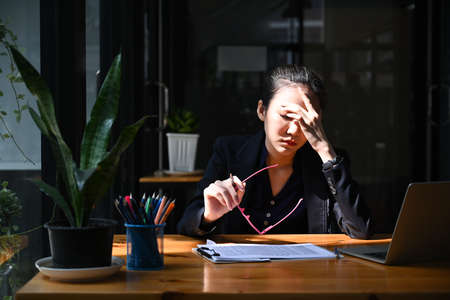 Overworked businesswoman take off glasses and massaging her head.の写真素材