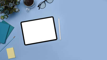 Creative workplace with digital tablet, stylus pen and notebook on blue background.の写真素材