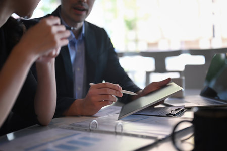 Cropped shot two businesspeople using digital tablet and analyzing financial data together.の写真素材