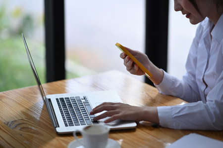Businesswoman working with laptop and using smart phone in office.の写真素材