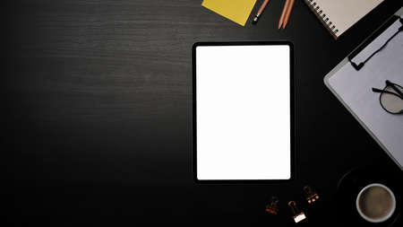 Mock up digital tablet, clipboard and coffee cup on black table.