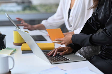 Cropped shot two businesswoman sitting together in modern workplace.の写真素材