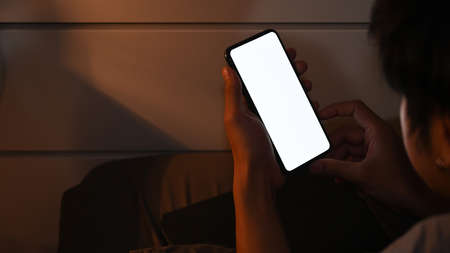 Close up view young man using smart phone at late night while lying in bed.