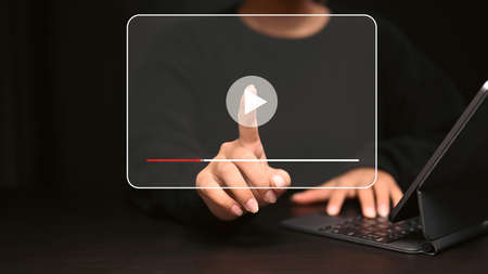 Young woman using computer tablet and pressing on play button virtual screen.の写真素材