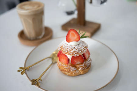 Vanilla choux cream puff with fresh  strawberries on white plate.の写真素材