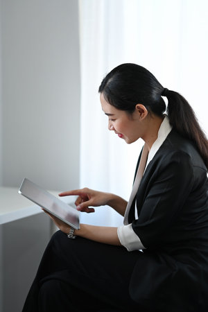Confident young businesswoman sitting at her office desk and smiling to camera.