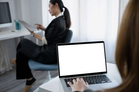 Two young businesswomen reading financial document together at a boardroom.の写真素材