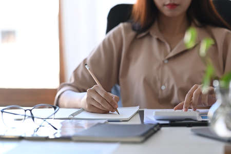 Portrait of smiling businesswoman sitting in modern workplace an working with laptop.