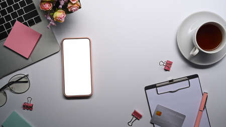 Flat lay, mockup smart phone with empty screen on white office desk.