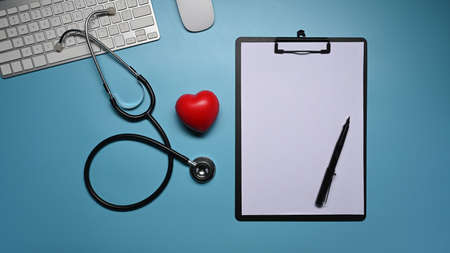 Top view, clipboard, stethoscope and red heart on blue background. Healthcare and medical concept.の写真素材